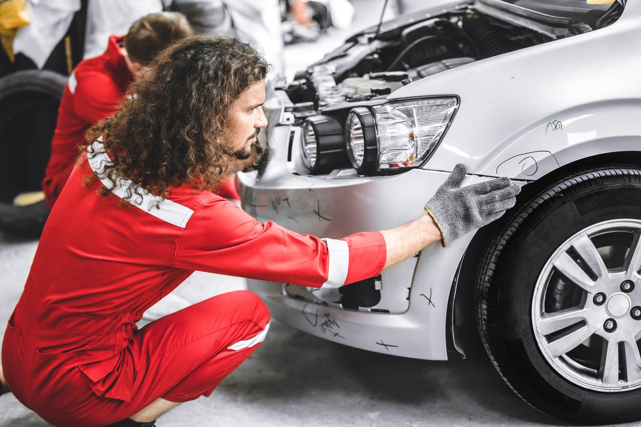 A mechanic fixing a car that was in a collision.